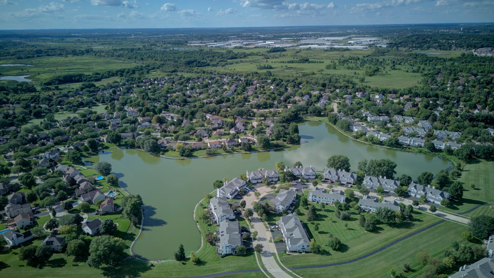 Aerial view of Woodland Hills in Bartlett IL, showing the main lake with single-family homes on the west shore and townhomes on the east
