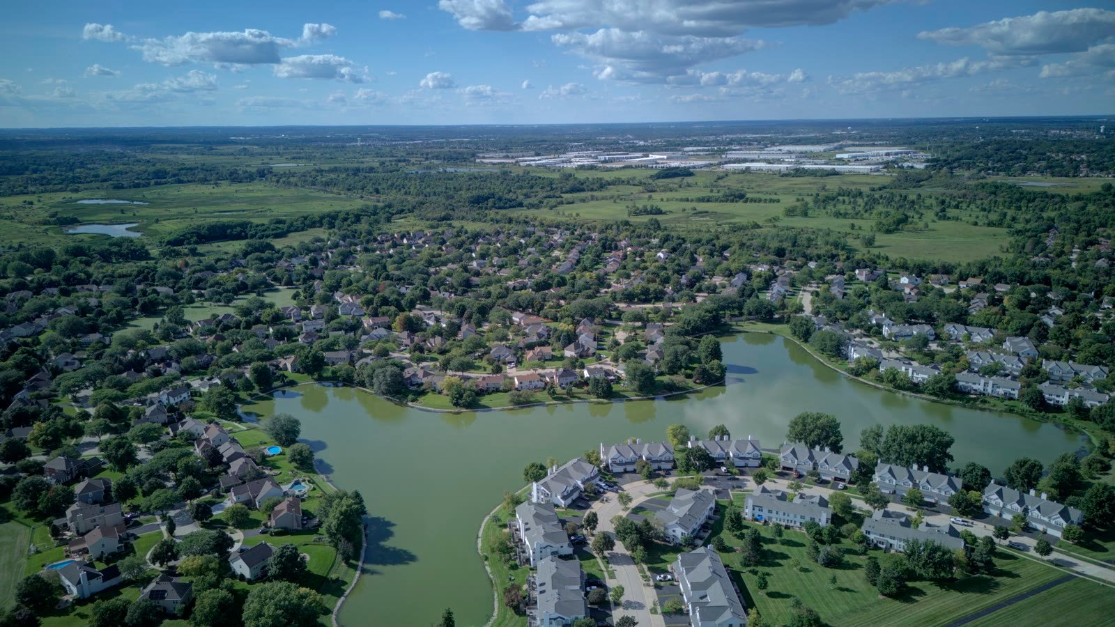 Wide aerial of Woodland Hills Bartlett IL looking north across the lake toward open prairie